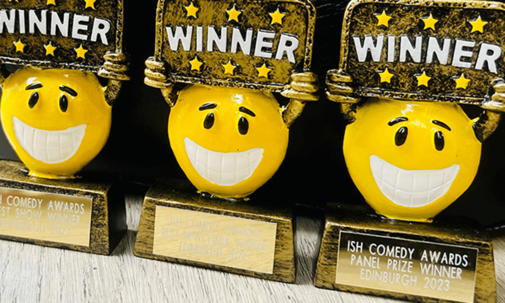 Three comedy award trophies with smiling yellow emoji faces labeled "winner," inscribed with "15th comedy awards panel prize winner edinburgh 2023.
