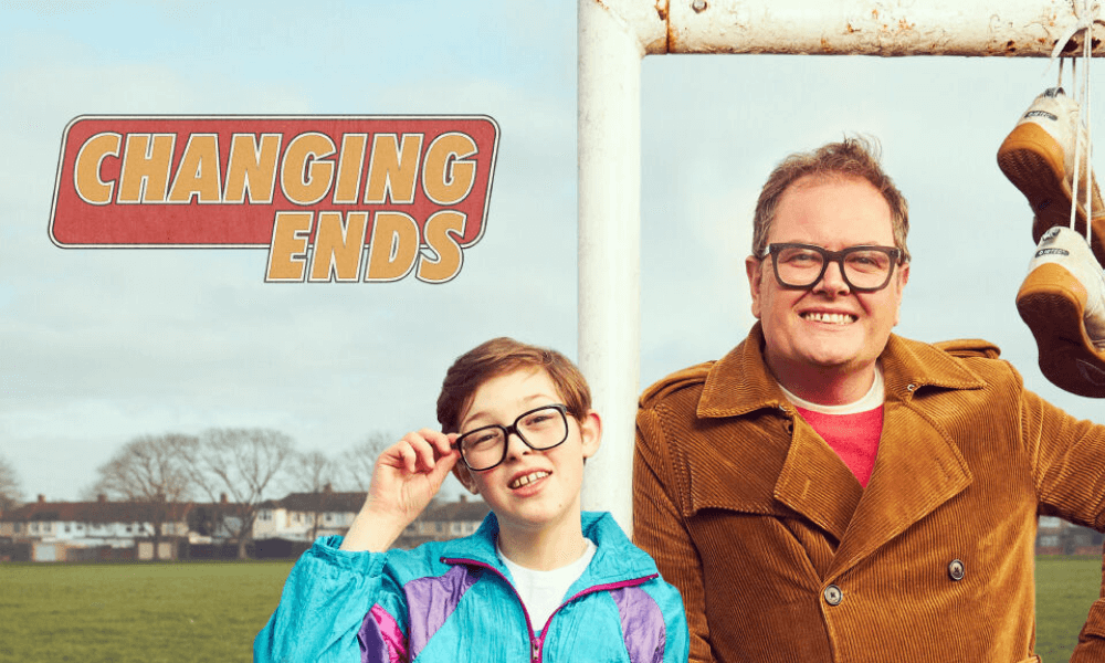 Promotional image for "changing ends" featuring a middle-aged man and a young boy, both smiling, with a football goalpost and hanging sneakers in the background.